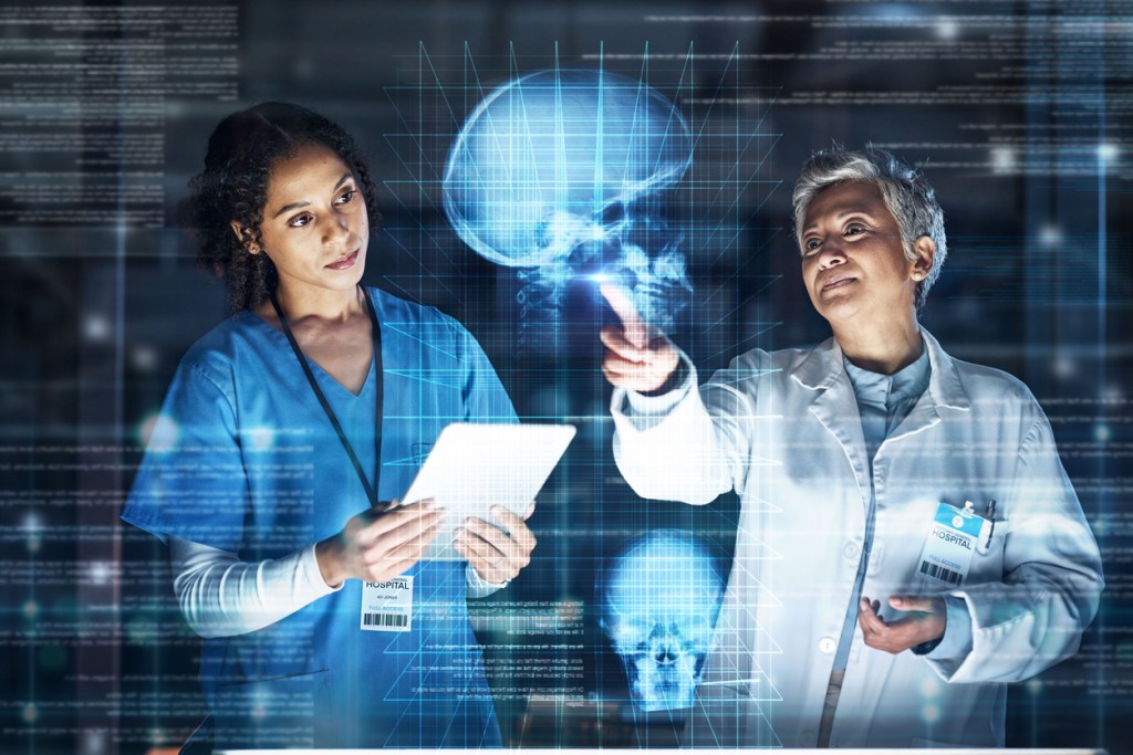 Two healthcare professionals discussing a digital brain scan while analyzing data on a tablet.